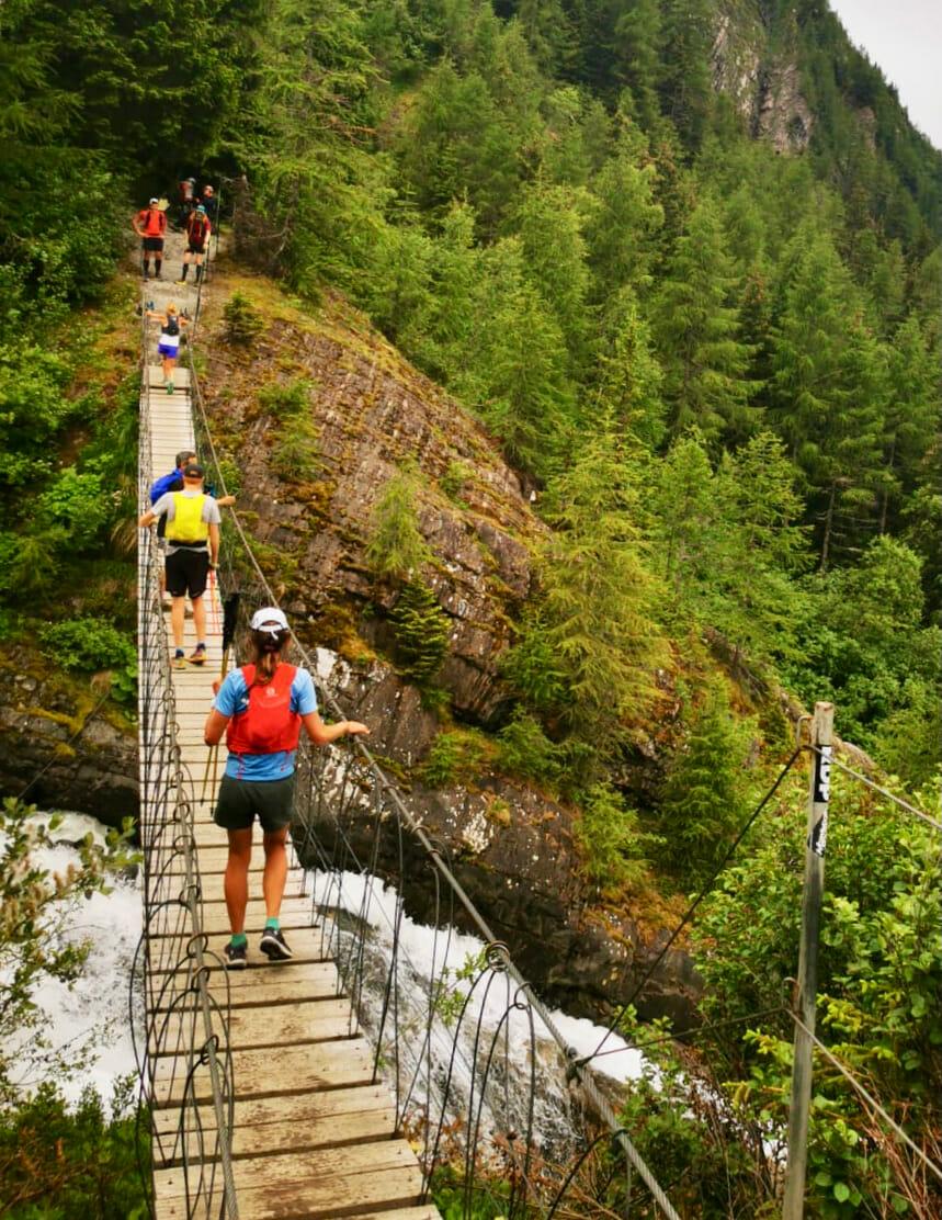 Trail runners crossing a suspension bridge