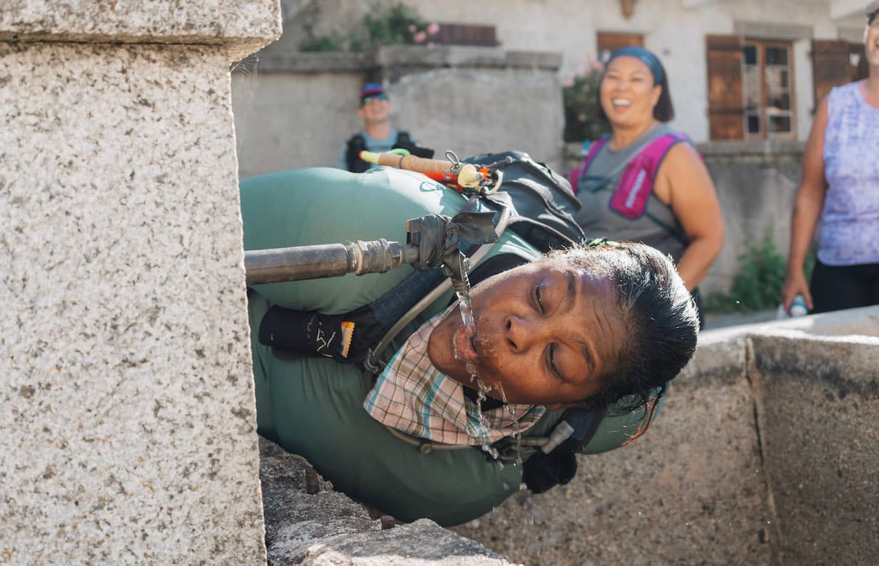 Mirna Valerio drinking from a water fountain in the Alps