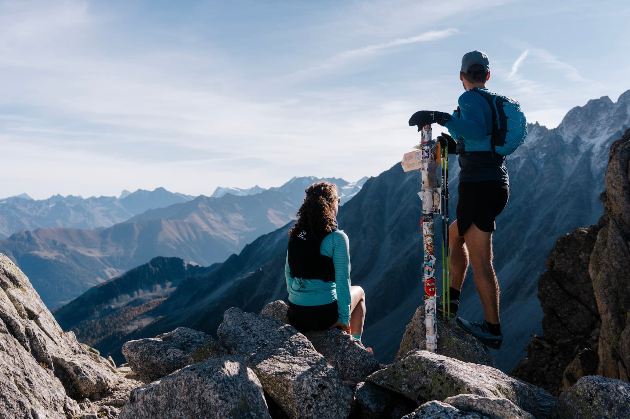 2 runners sit and look at the view at high mountain col