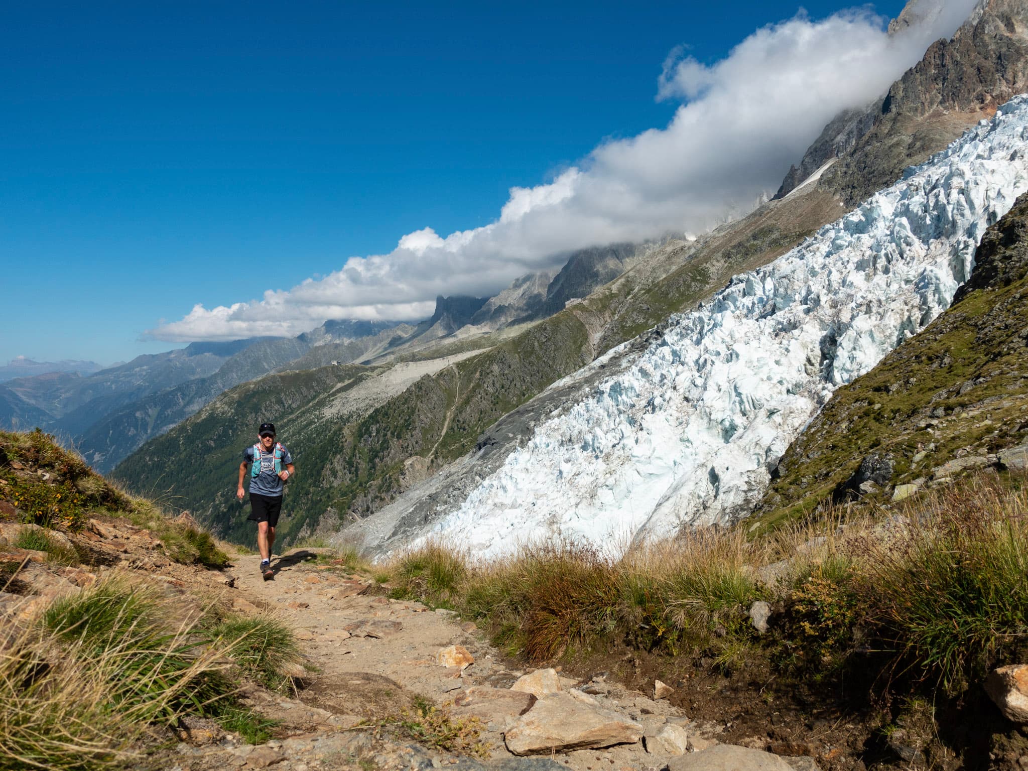 Runner runs up trail with glaciers and Chamonix valley below