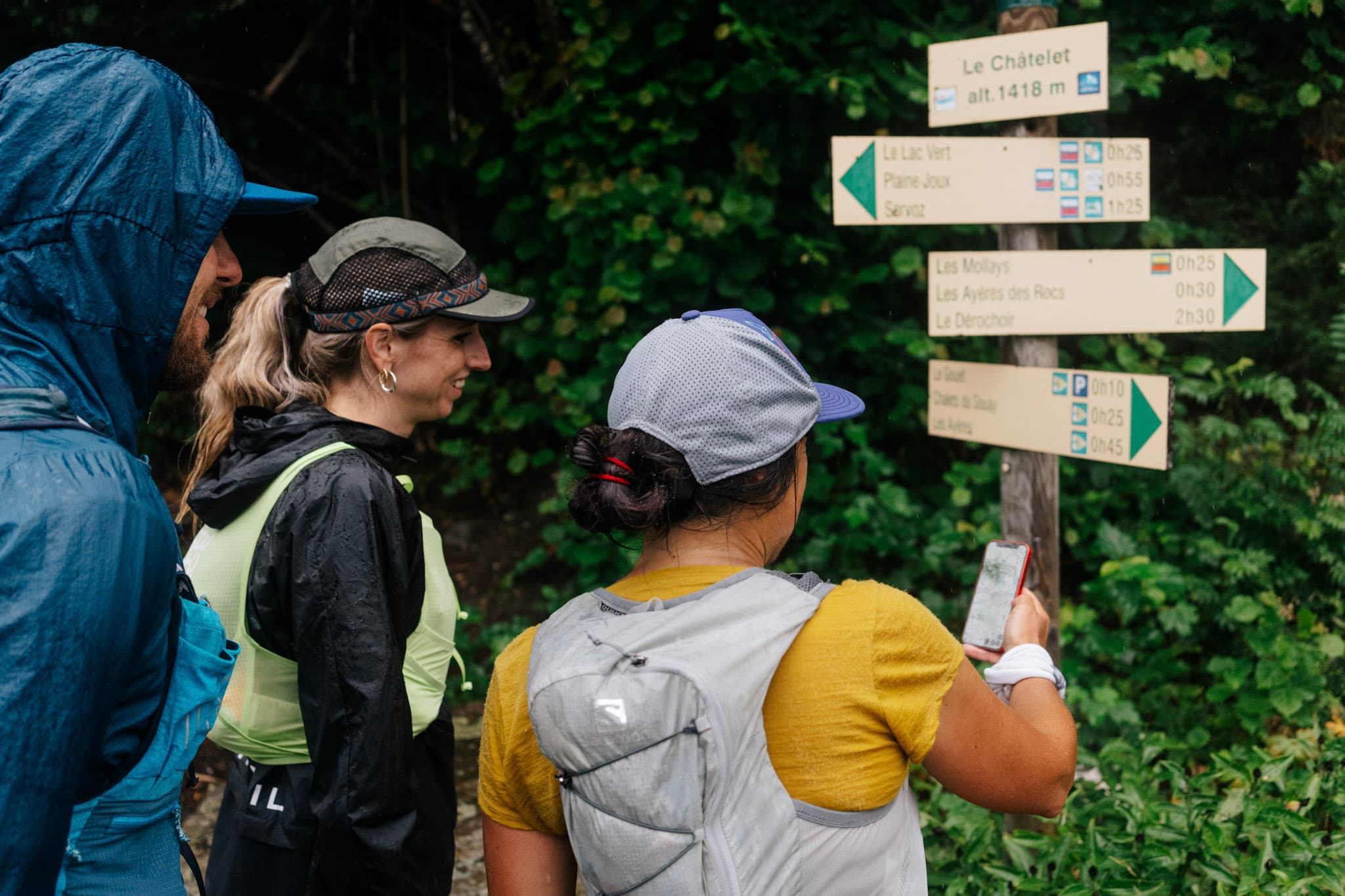 3 runners look at hiking sign post