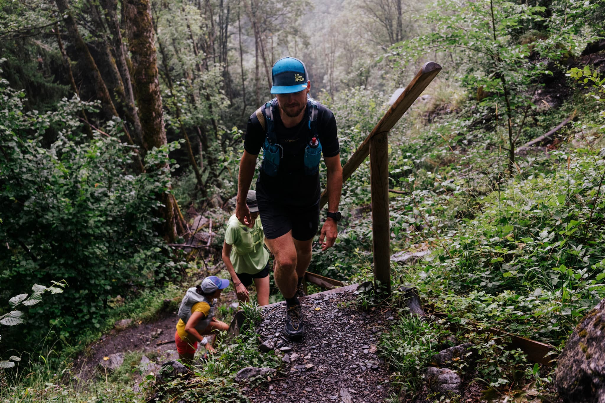 3 runner hike up through forest on wet day