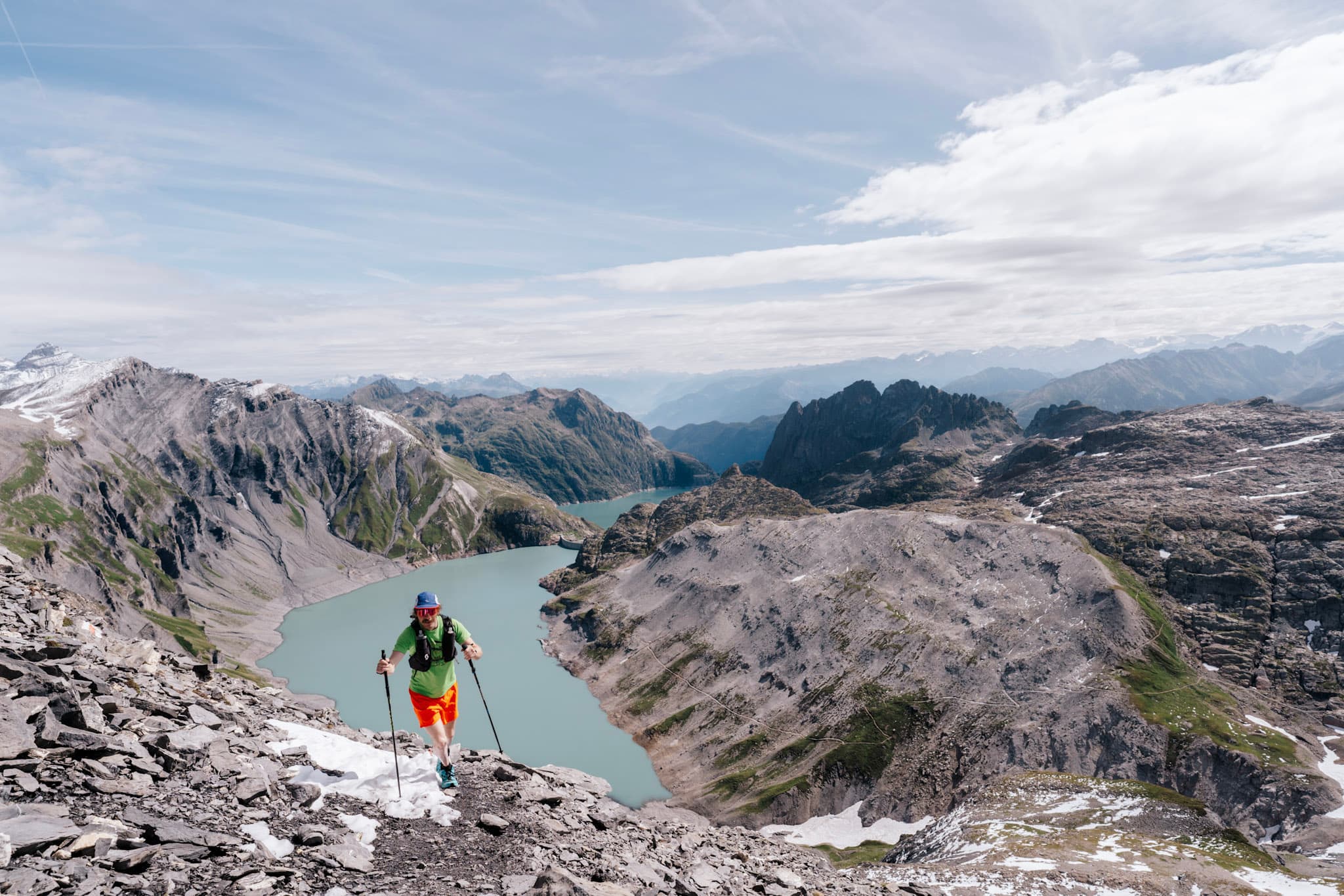 One runner hikes up, steep Rocky Trail with lake in the background