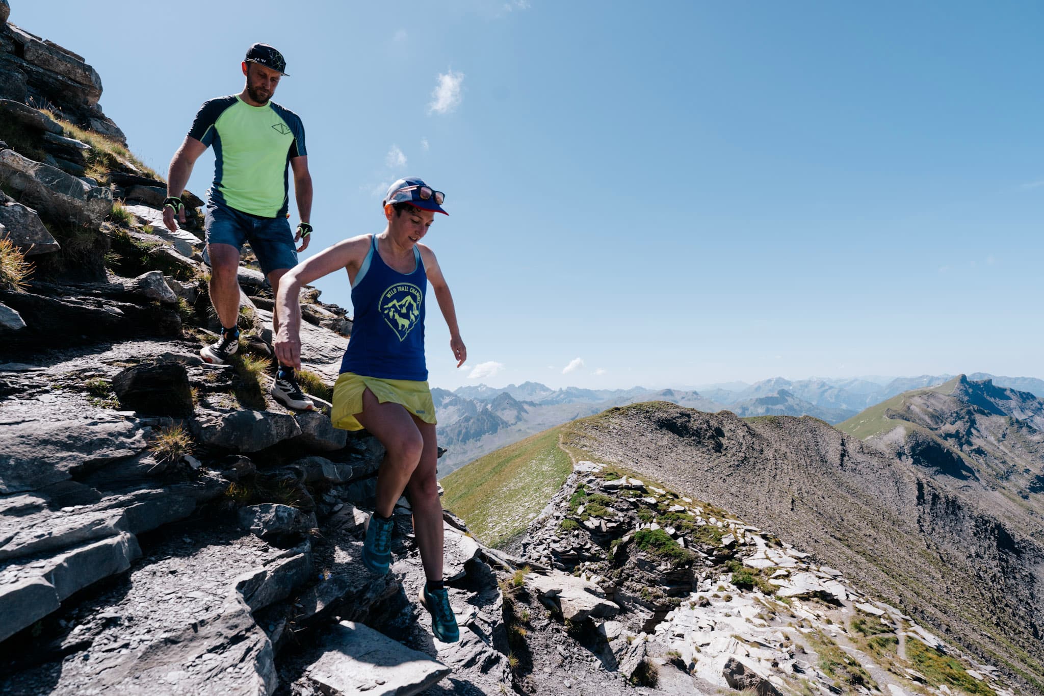 2 runners scramble down rocks from summit