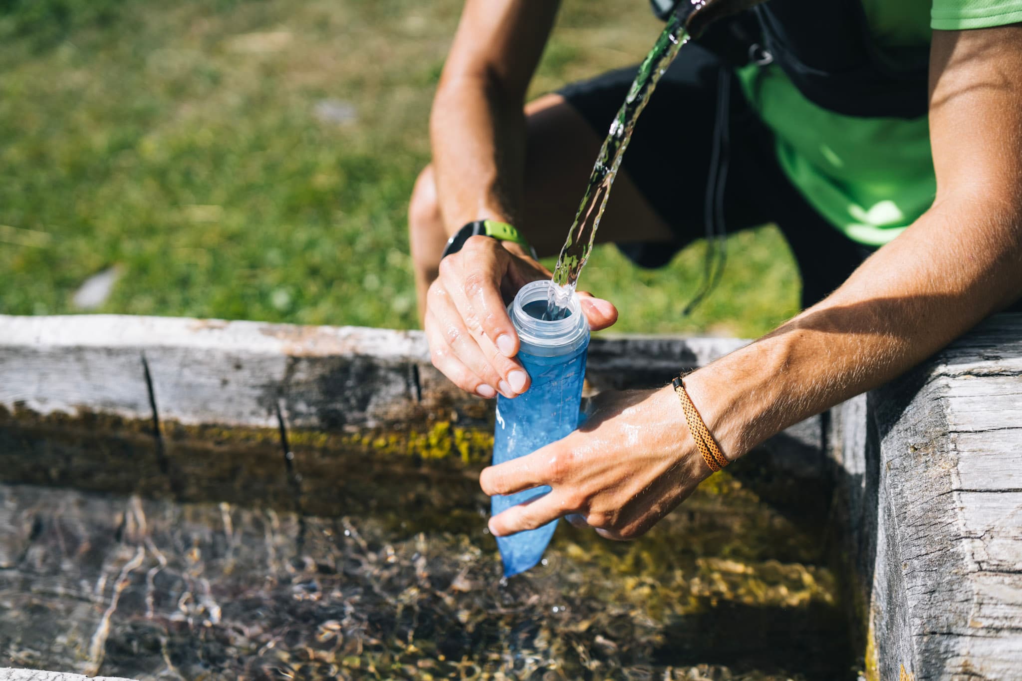 runner fills up soft flask from water trough