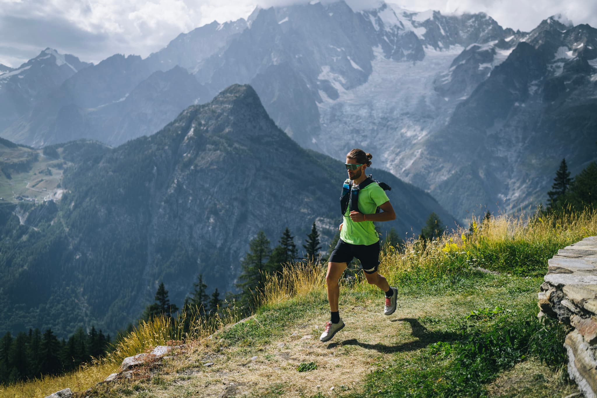 runner runs along trail with alpine mountains with glaciers in background