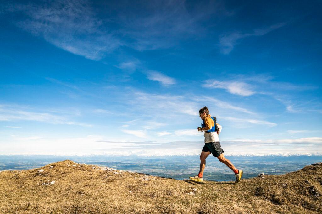 Xavier Thévenard running along the crest of the Jura mountains with the Alps in the distance.