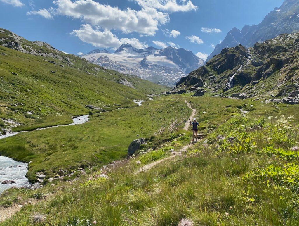 A trail runner running alongside a stream on the Tor des Giants route in the Gran Paradiso National Park.