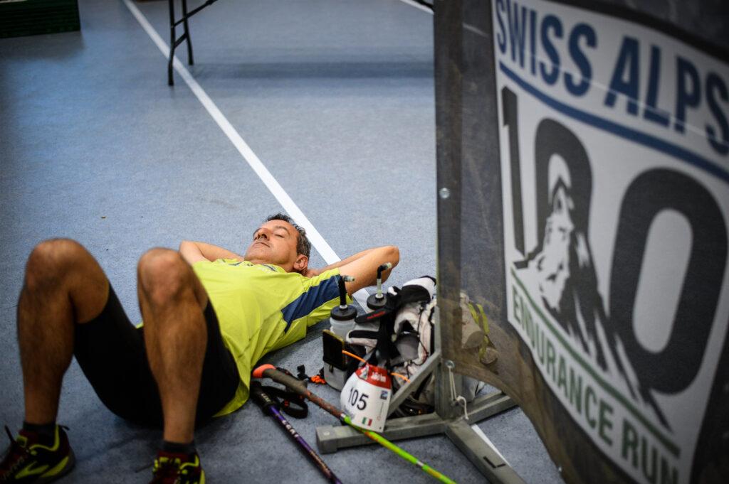 runner sleeping near a swiss alps 100 endurance run sign