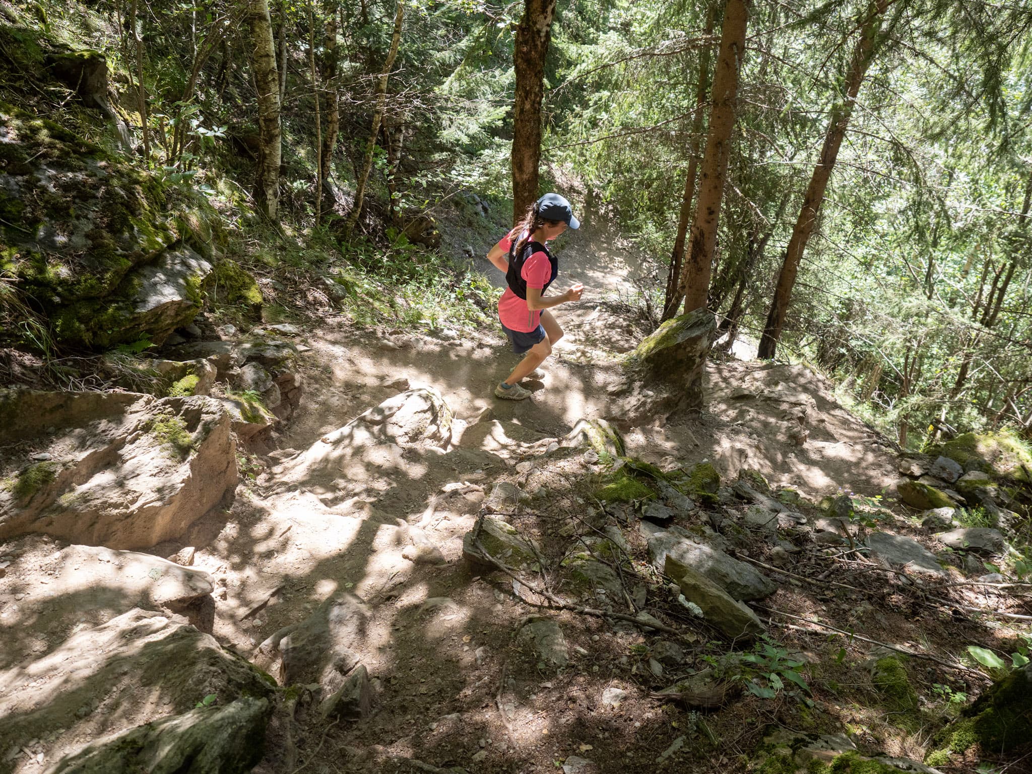 Runner running down hill on steep trail in forest