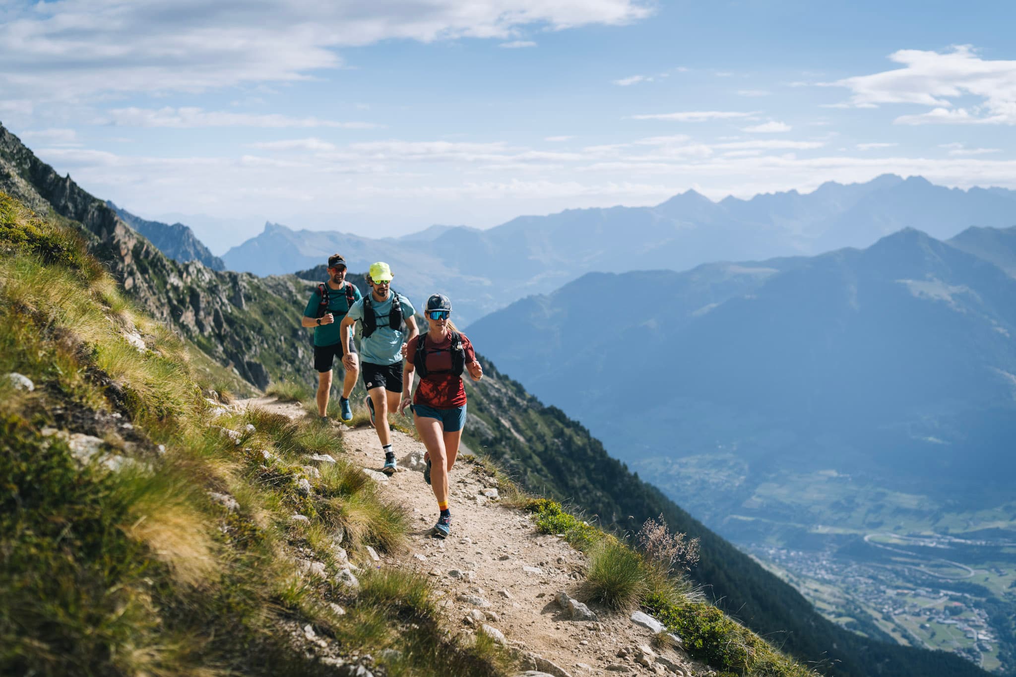 3 runners on perfect single trail running with mountains in background