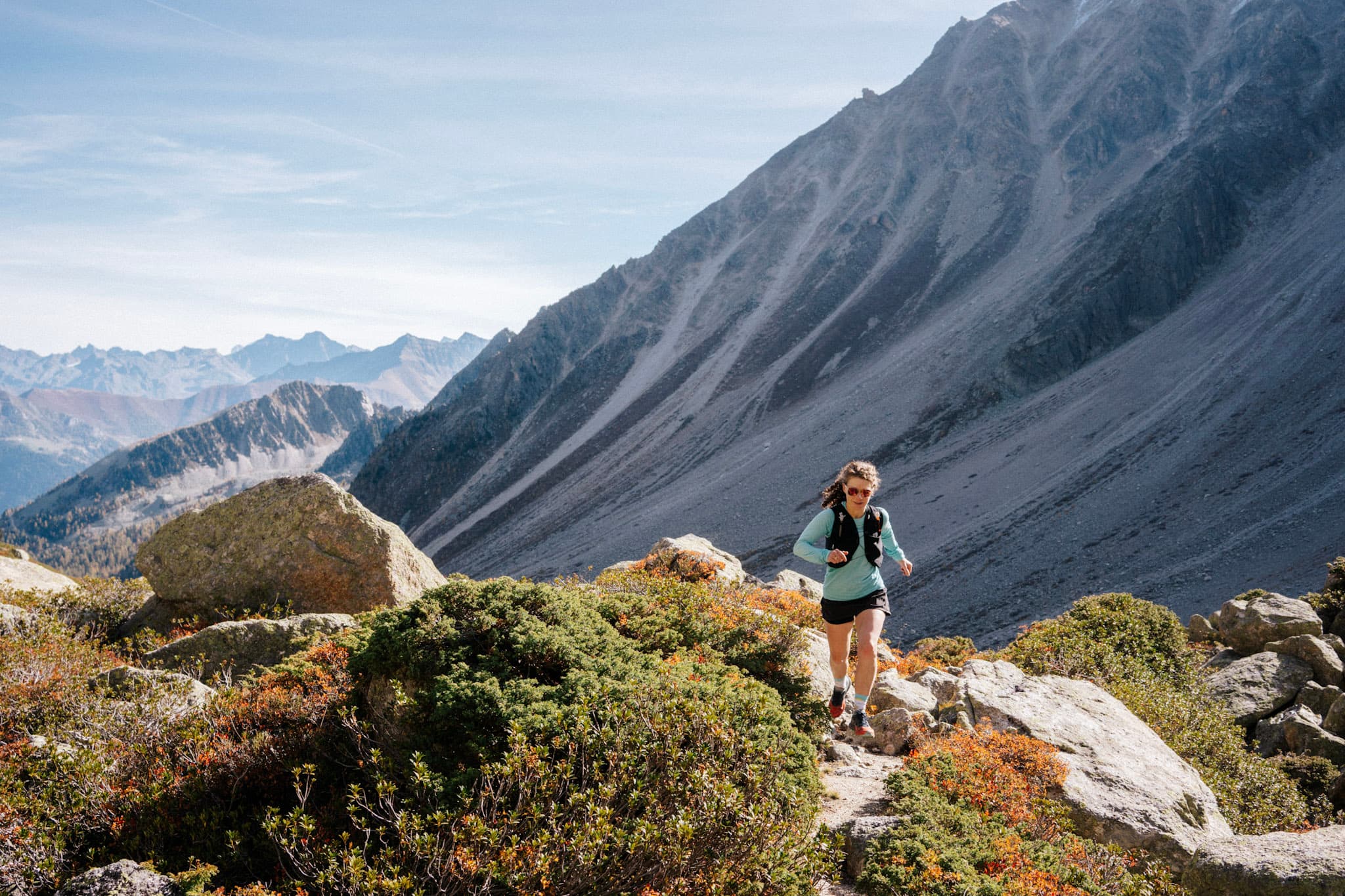 Runner runs uphill with scree slopes behind