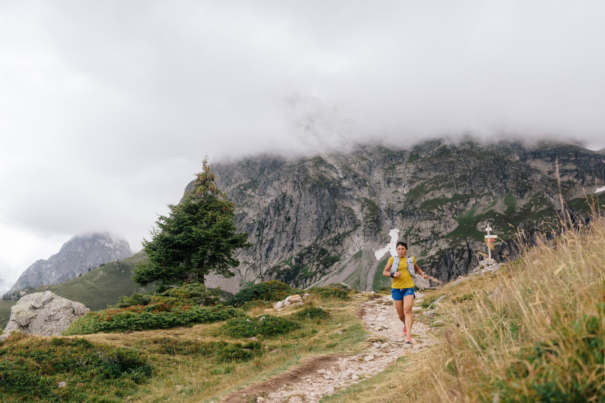 Runner runs down trail with cliffs in background