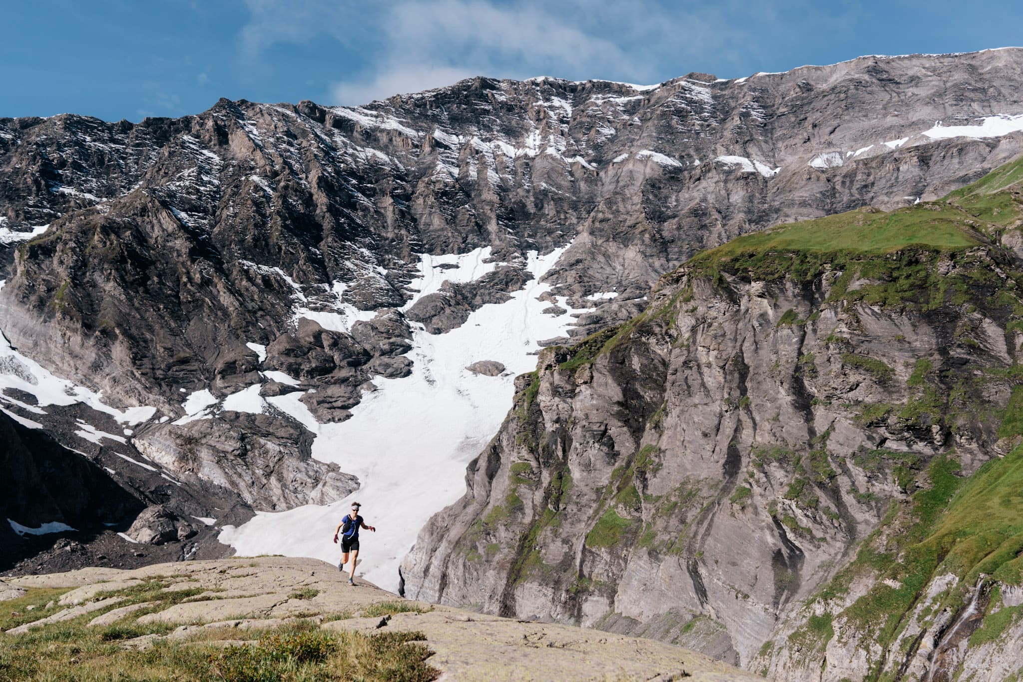 Runner with cliffs and snow behind