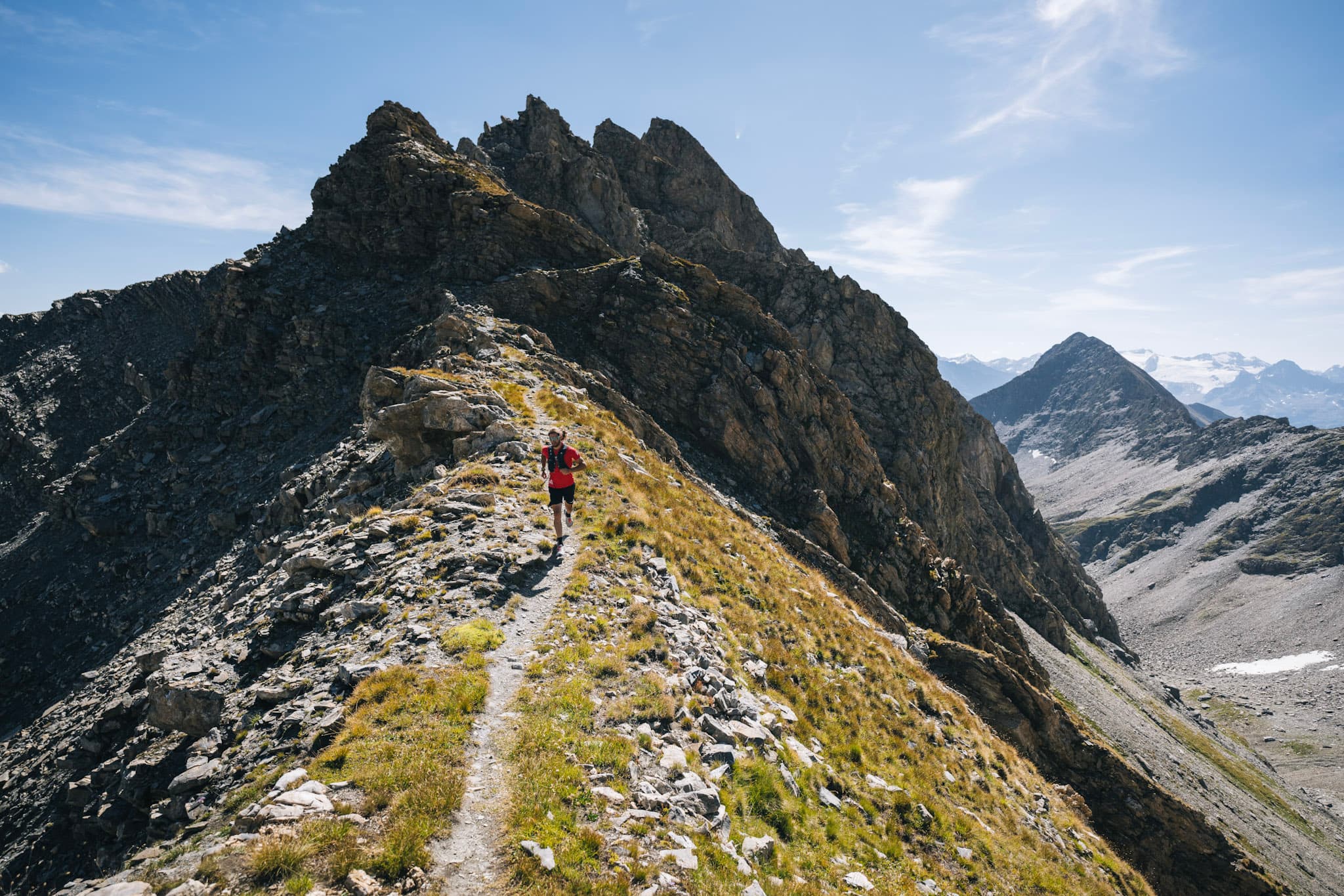 runner on single truck on ridge line with rocky summits behind