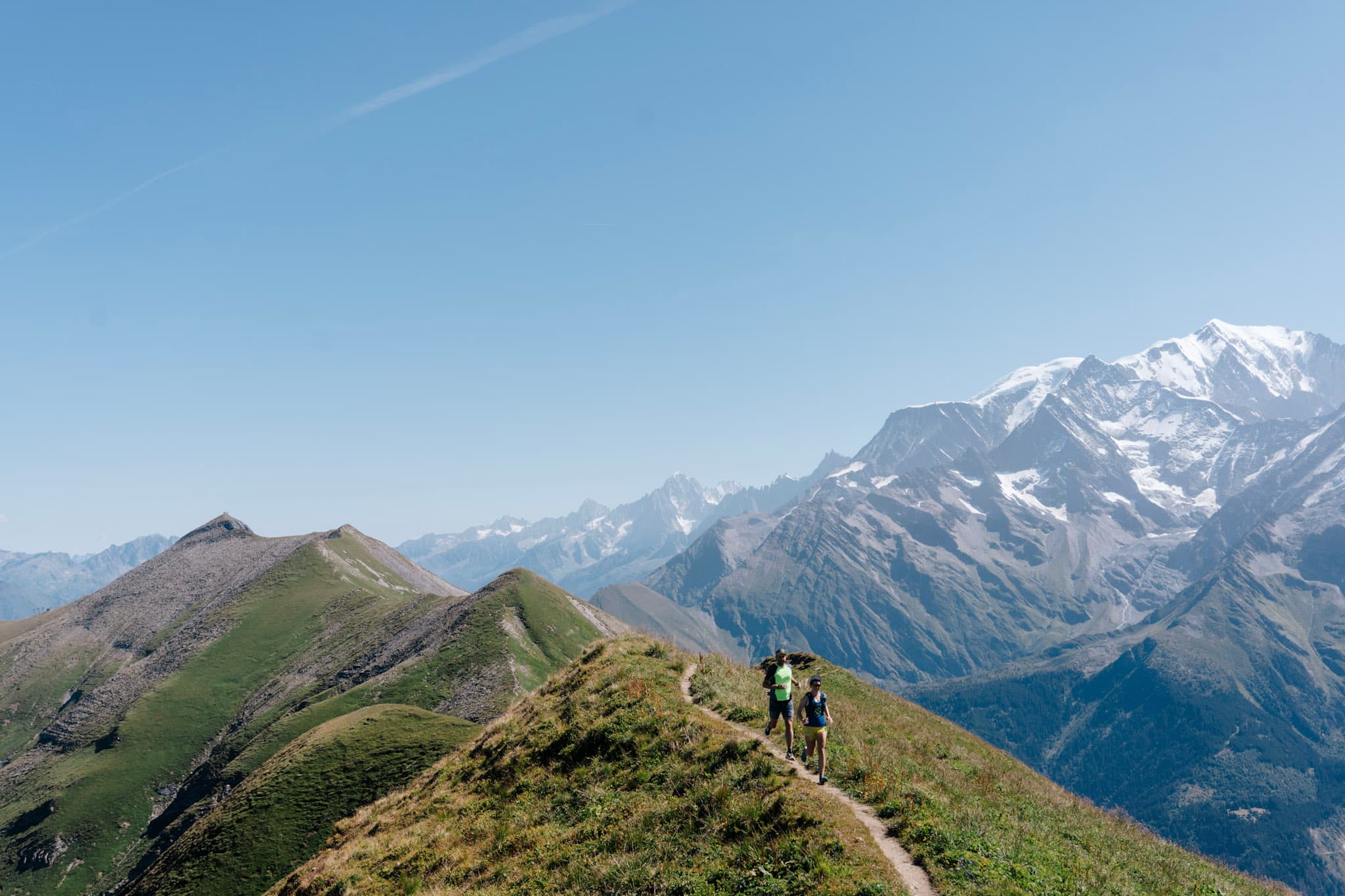 2 runners on grassy ridgeline trail