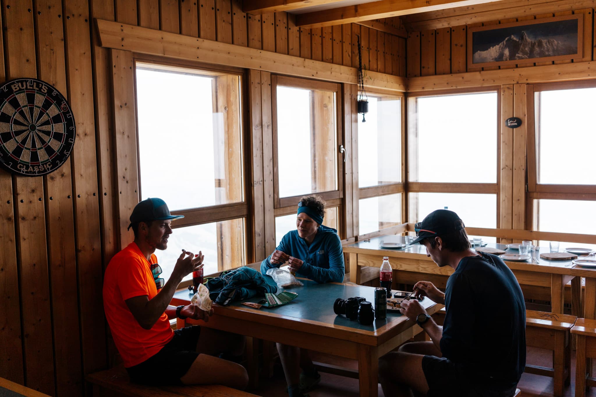 3 runners sat around table in mountain hut