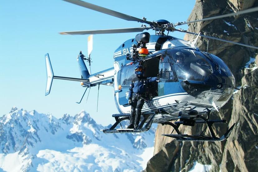 A rescue helicopter in the air near a cliff.