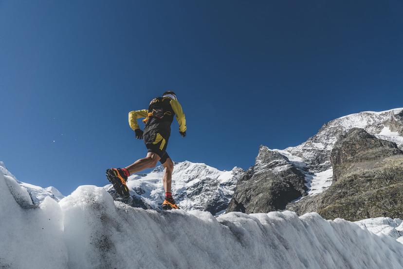 Trail runner in yellow jacket running on ice, taken from below