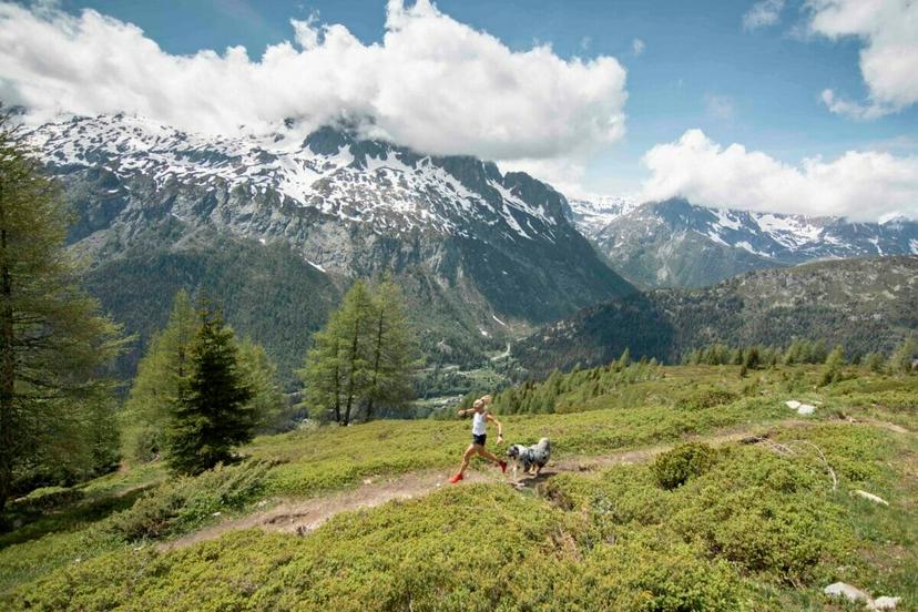 Mimmi Kotka in white shirt and with red shoes running on a single trail with dog