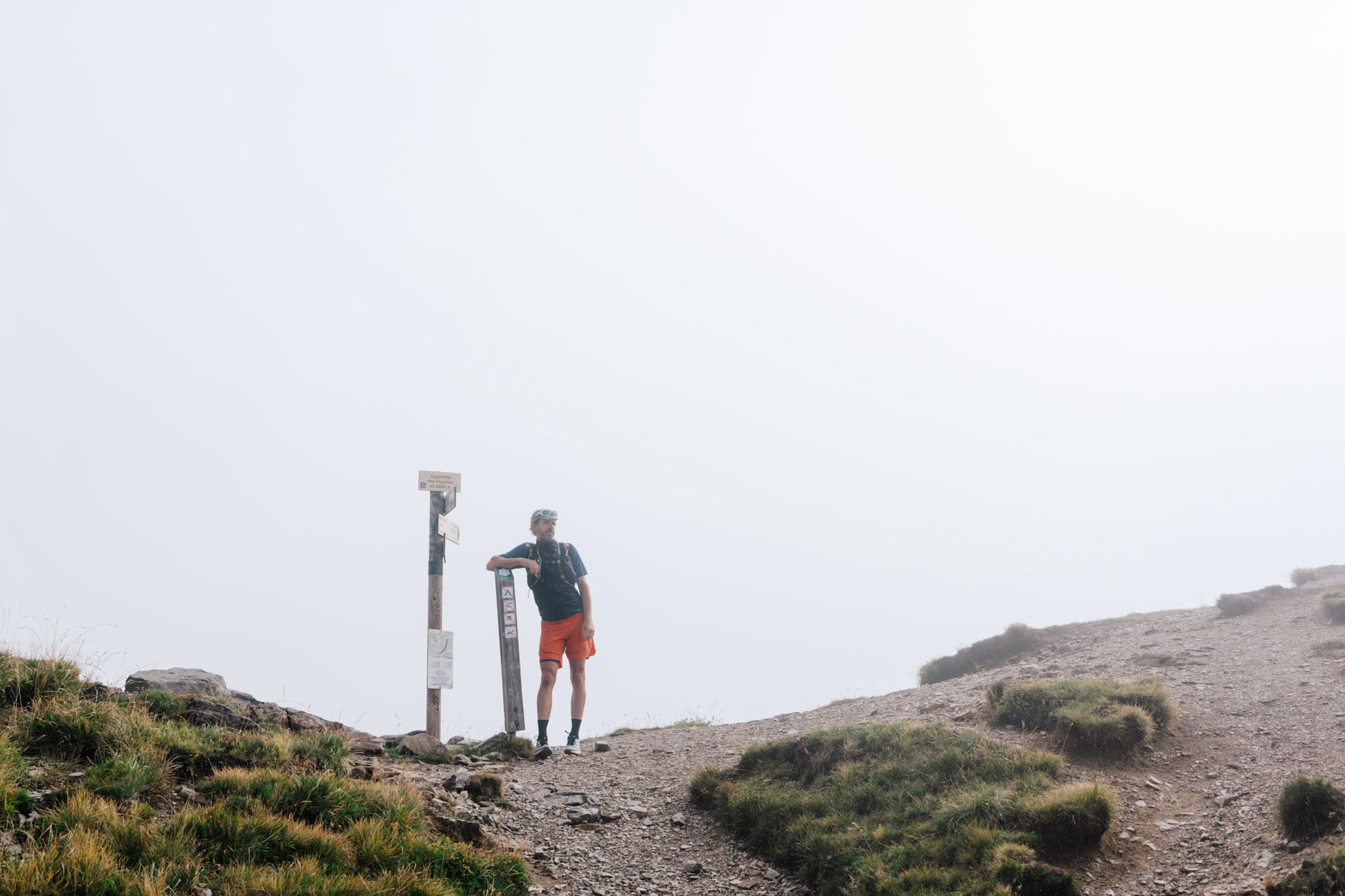 Runner stands at col next to signposts