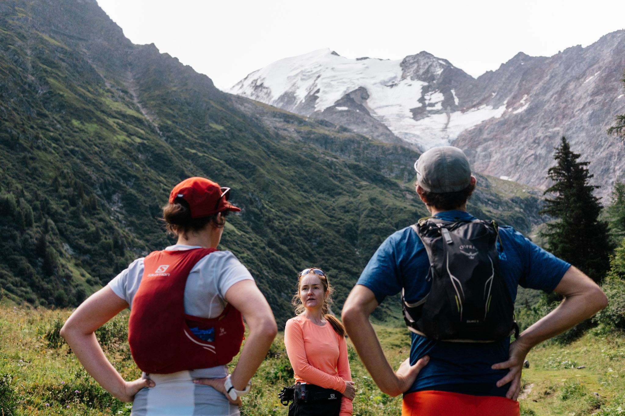 3 runner take a break with forest and alpine mountains behind