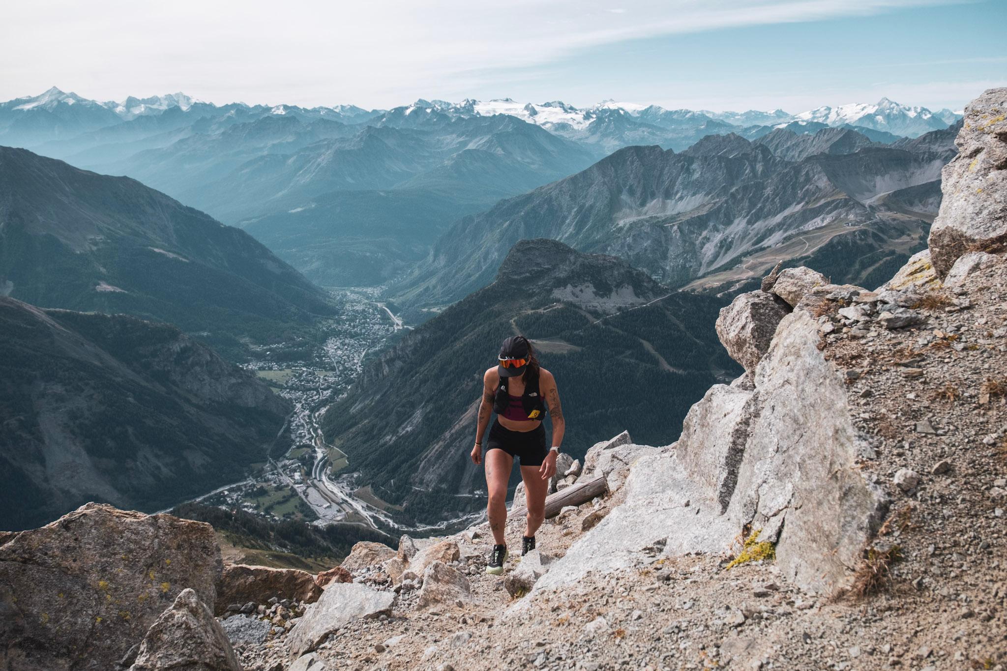 runner hikes uphill with valley in background