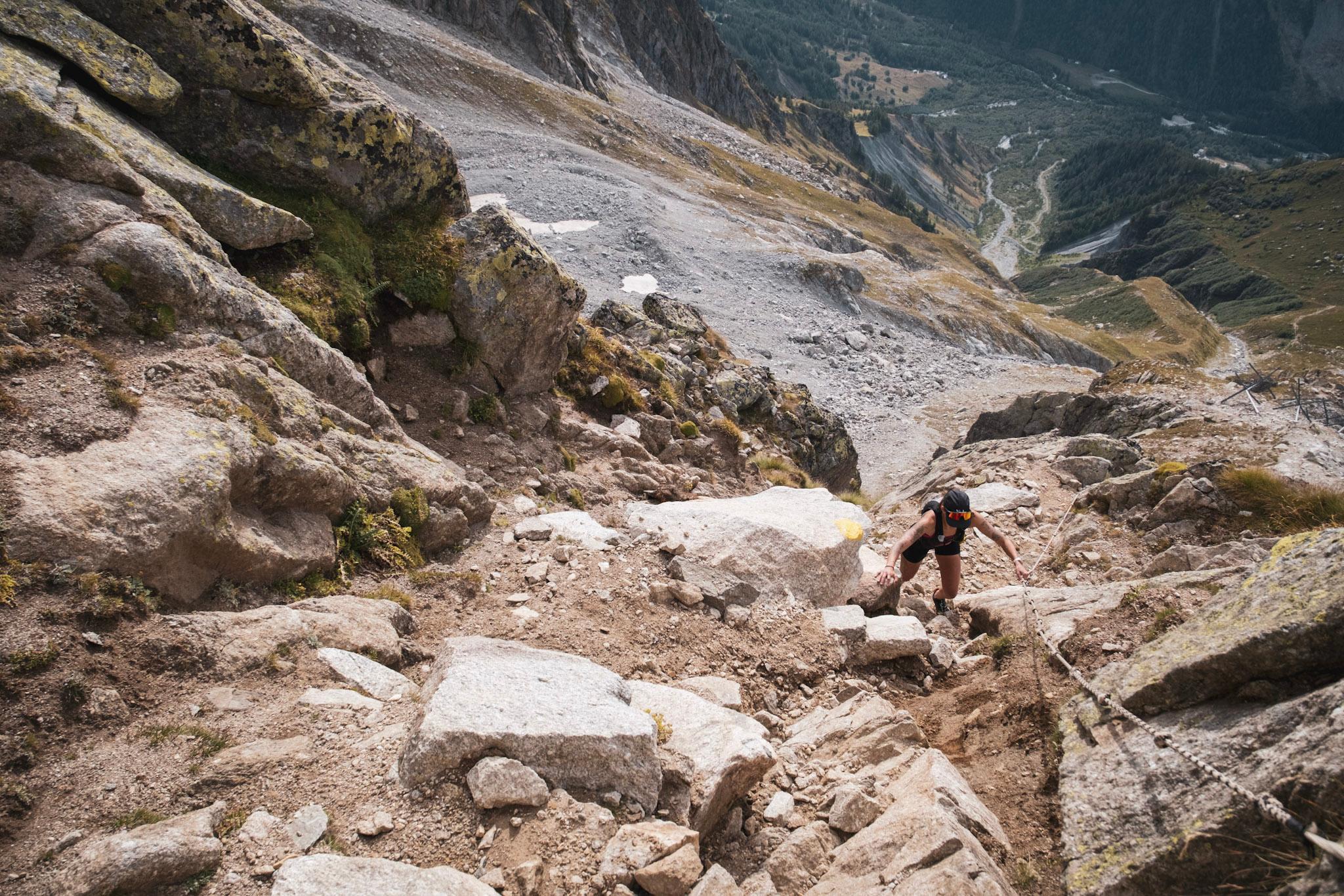 runner scrambles up technical rocky gully using handling for support