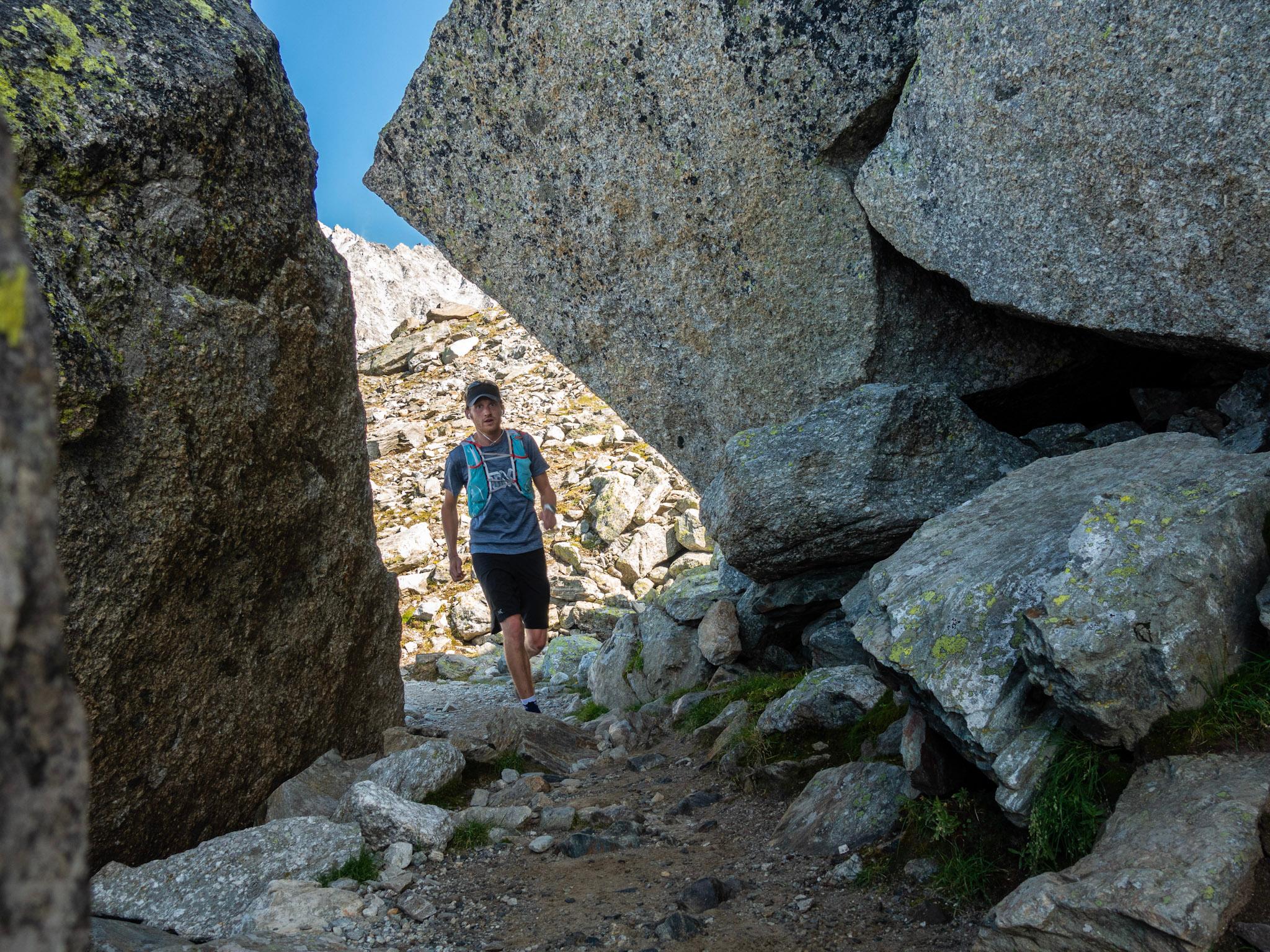 runner on rock trails with large boulders either side