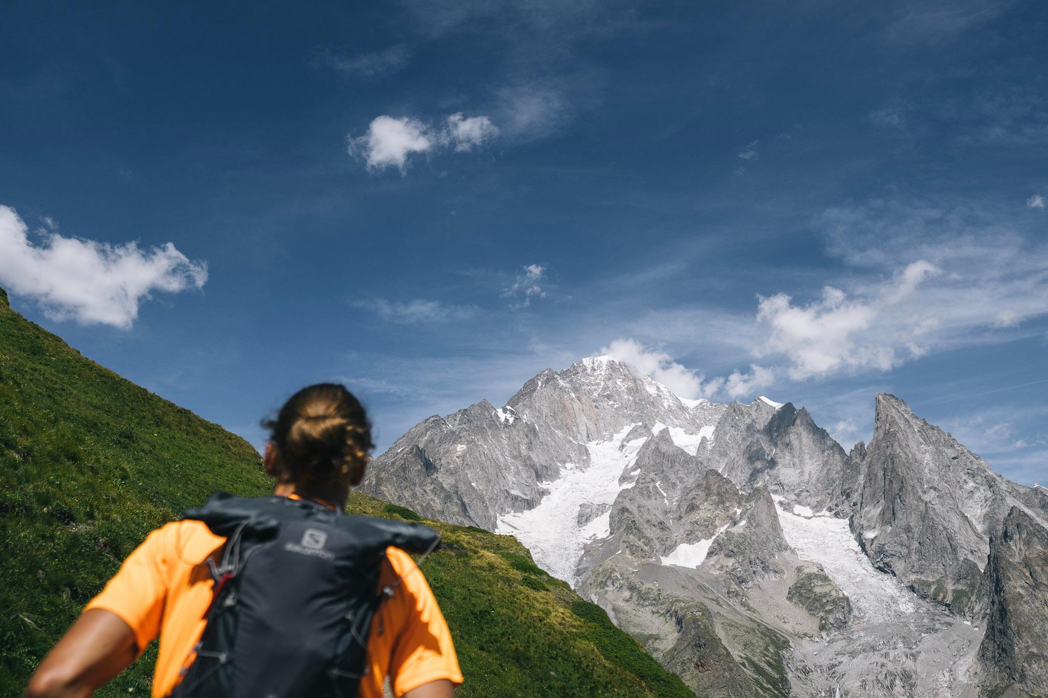 runner runs away from the camera towards big alpine mountains