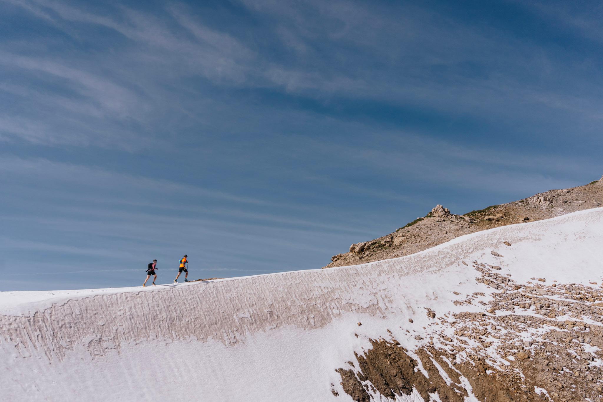 two runners run up snowy Ridge