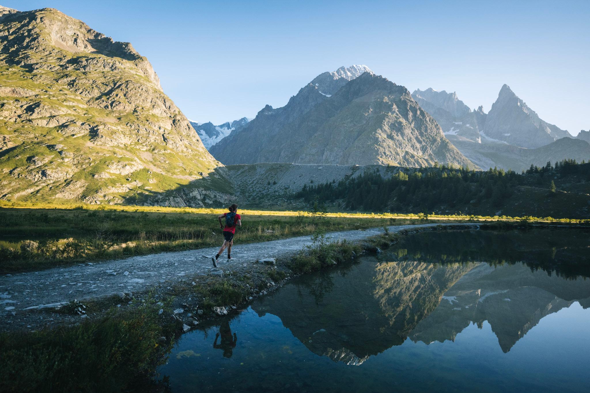 Runner next to lake with mountain reflection