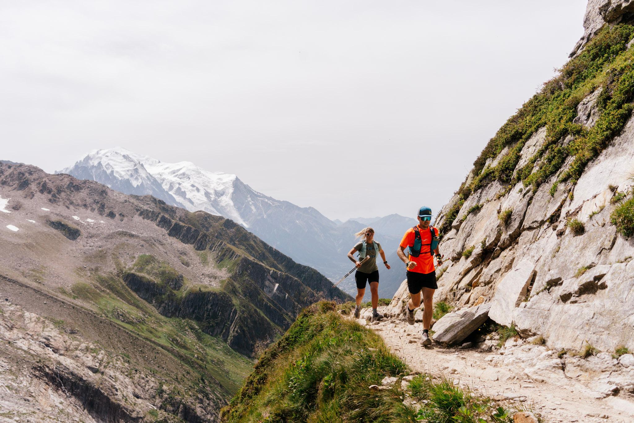 2 runners run along mountain trail with Mont Blanc behind