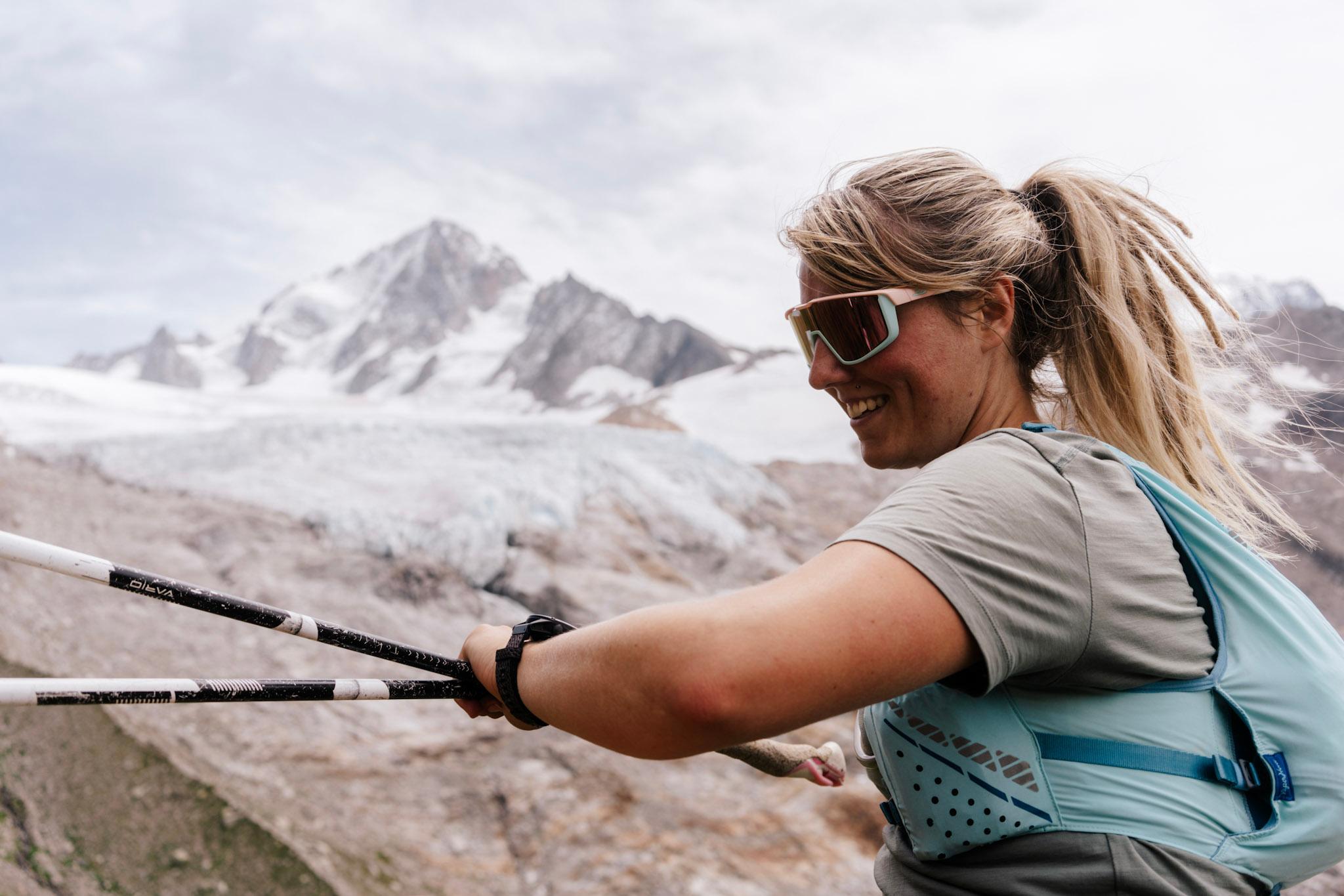 female runner looks at her watch with alpine mountains behind