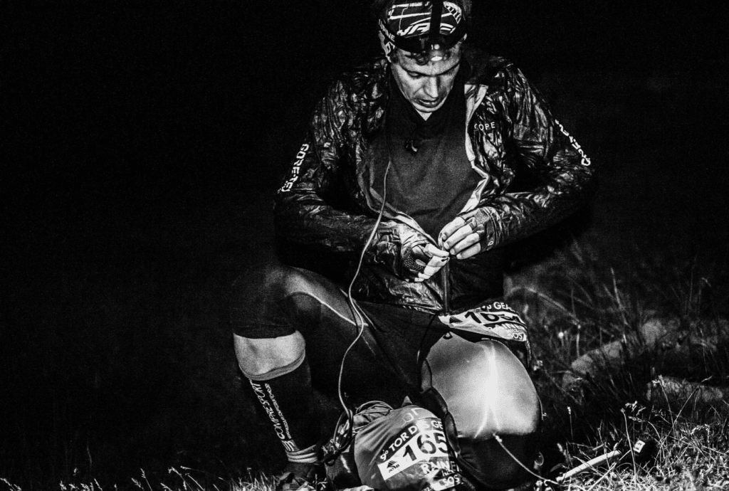 A runner takes a moment to readjust layers during the a middle-of-the-night break at Col Crosatie.