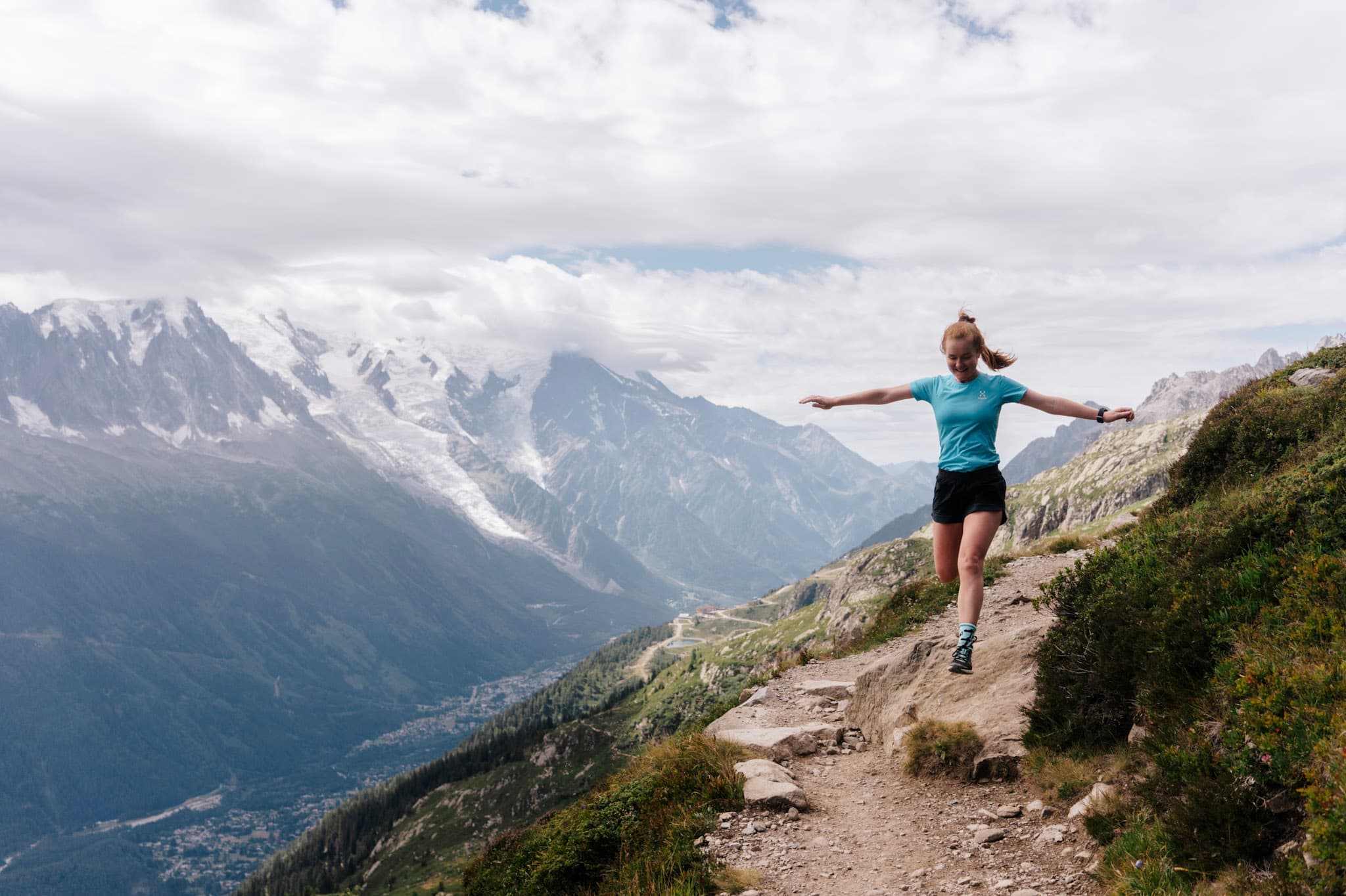Runner. Run runs downhill on Trail with glaciers and mountains in the background.