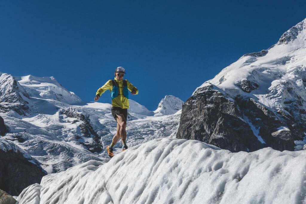 Trail runner with black shorts and yellow jacket running on a glacier