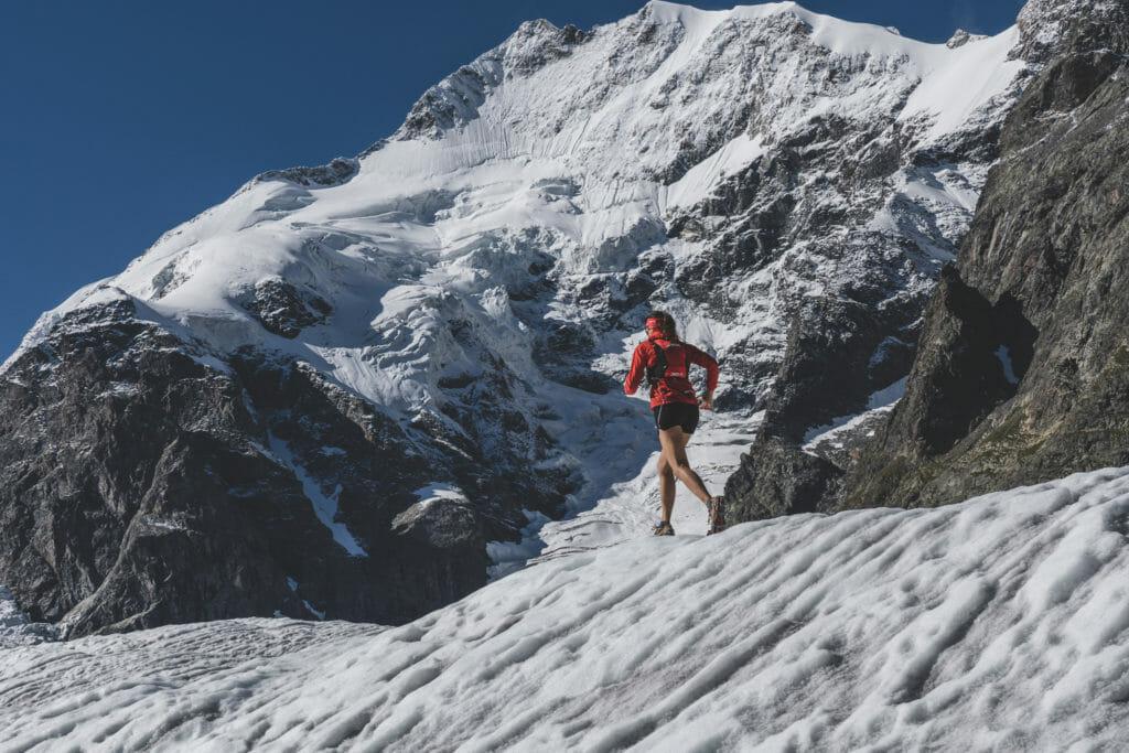 Female trail runner with shorts and black jacket running on glacier