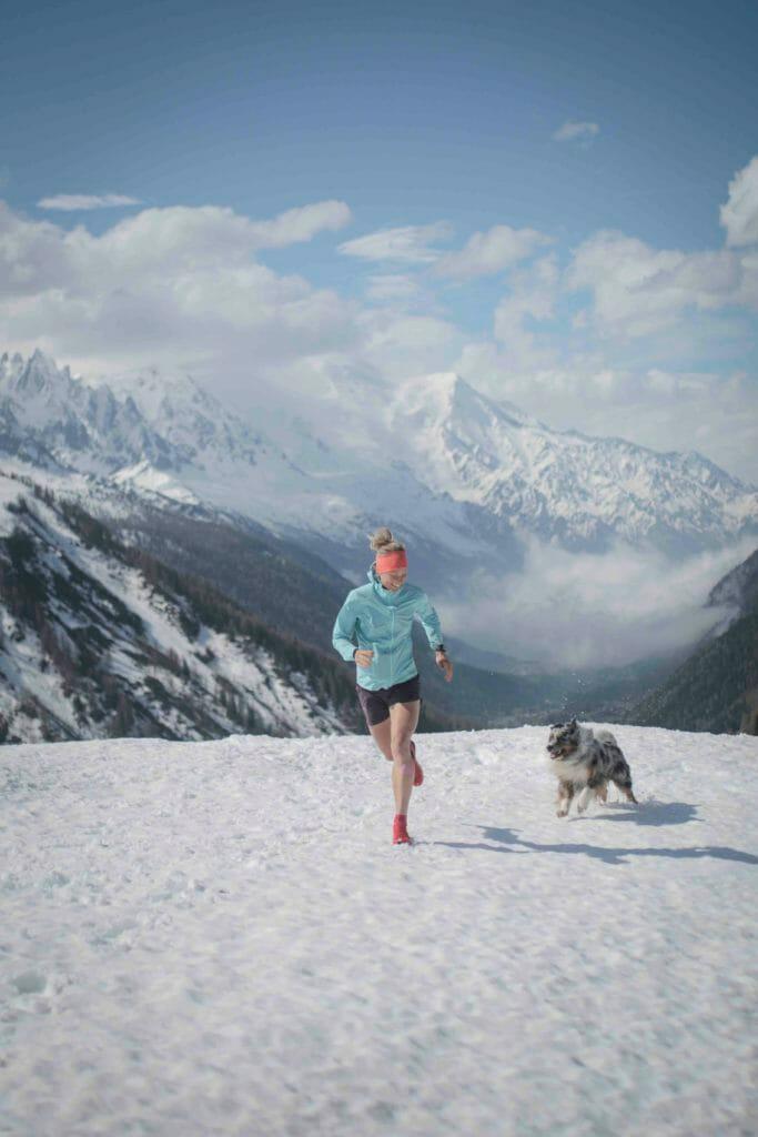 Mimmi Kotka in shorts running on snow with her dog