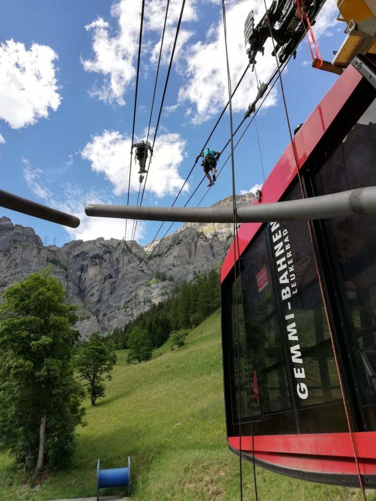 Two technicians climb along cables that support the Gemmi Bahn lift.
