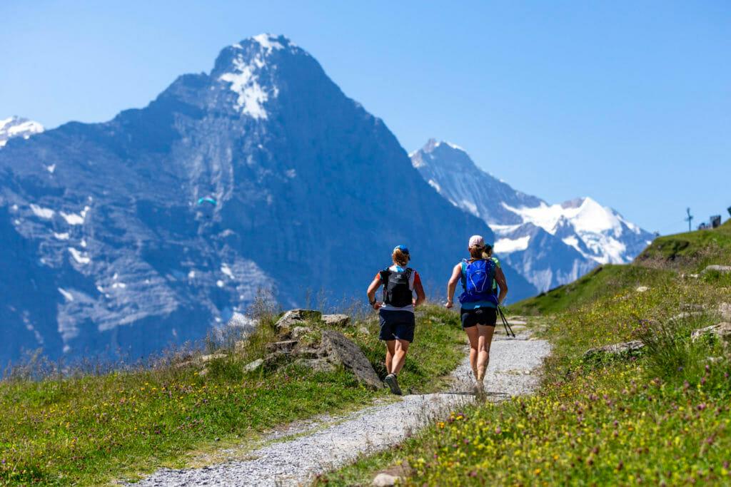 Two runners on a trail opposite the Eiger