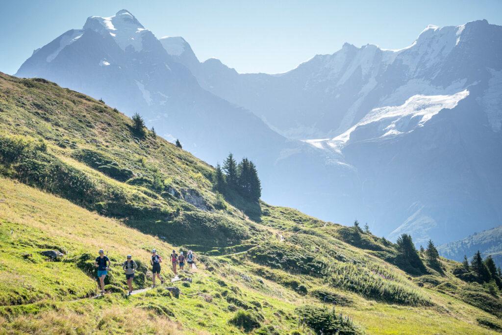 group running on trails below big mountains, Switzerland