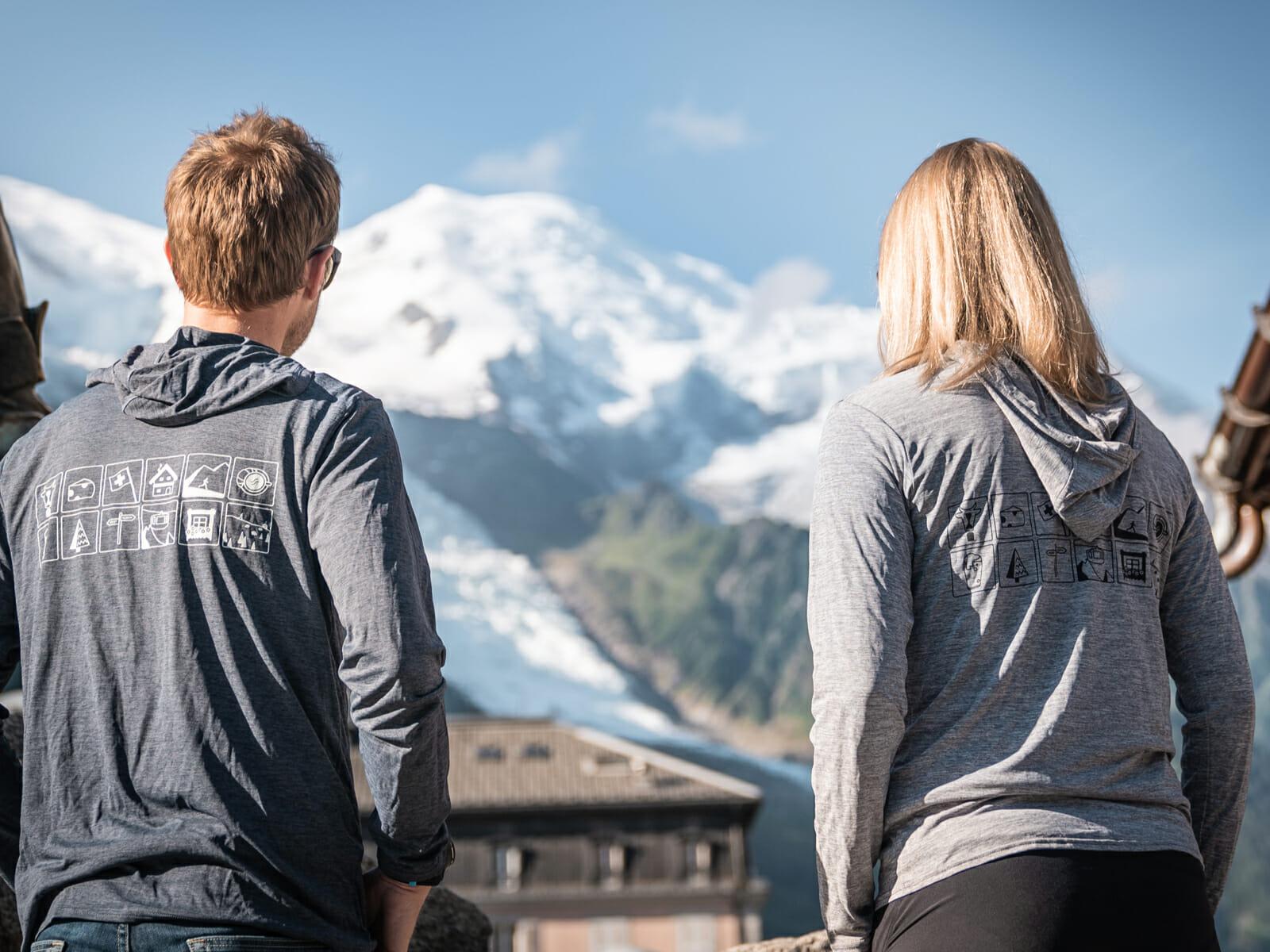 The back of Steph and Mike wearing grey Run the Alps hoodies, looking at the Mont Blanc