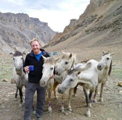 Bruno Yates with a blue mug and 5 white horses in Ladakh, Indian Himalaya