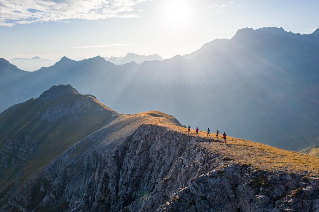 Five trail runners on a ridge in Malbun with sun rays