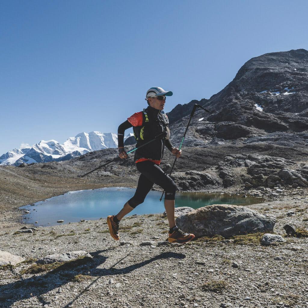Roberto Rivola running along a small mountain lake in the Engadine