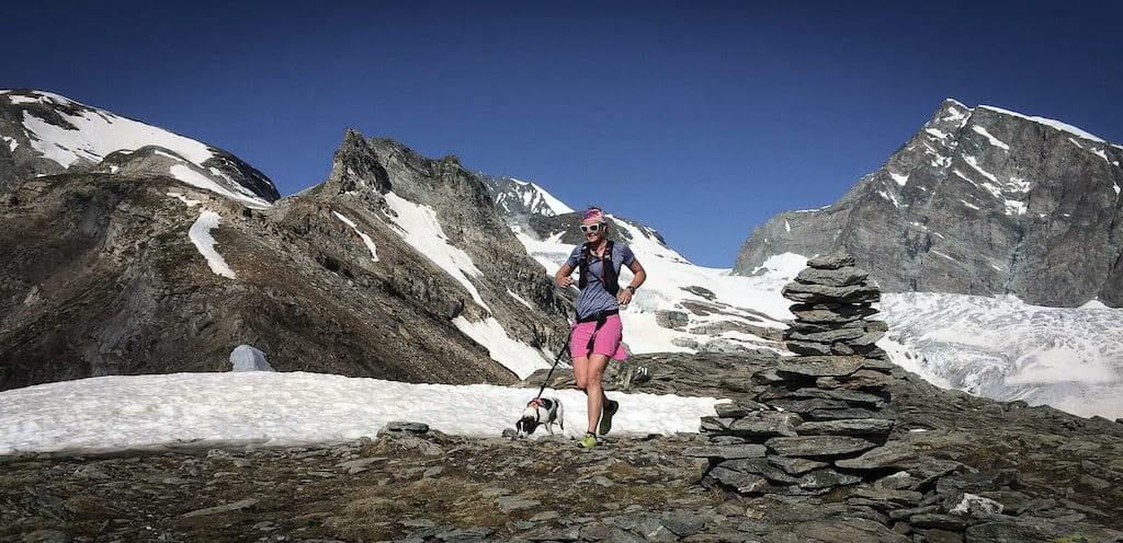 iebrig Scheeres running with her dog past a cairn with glacier in the Saas Fee valley