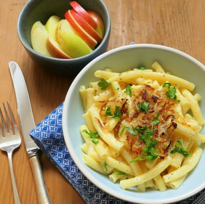 A bowl with Swiss macaroni and cheese and a little bowl with pieces of apple