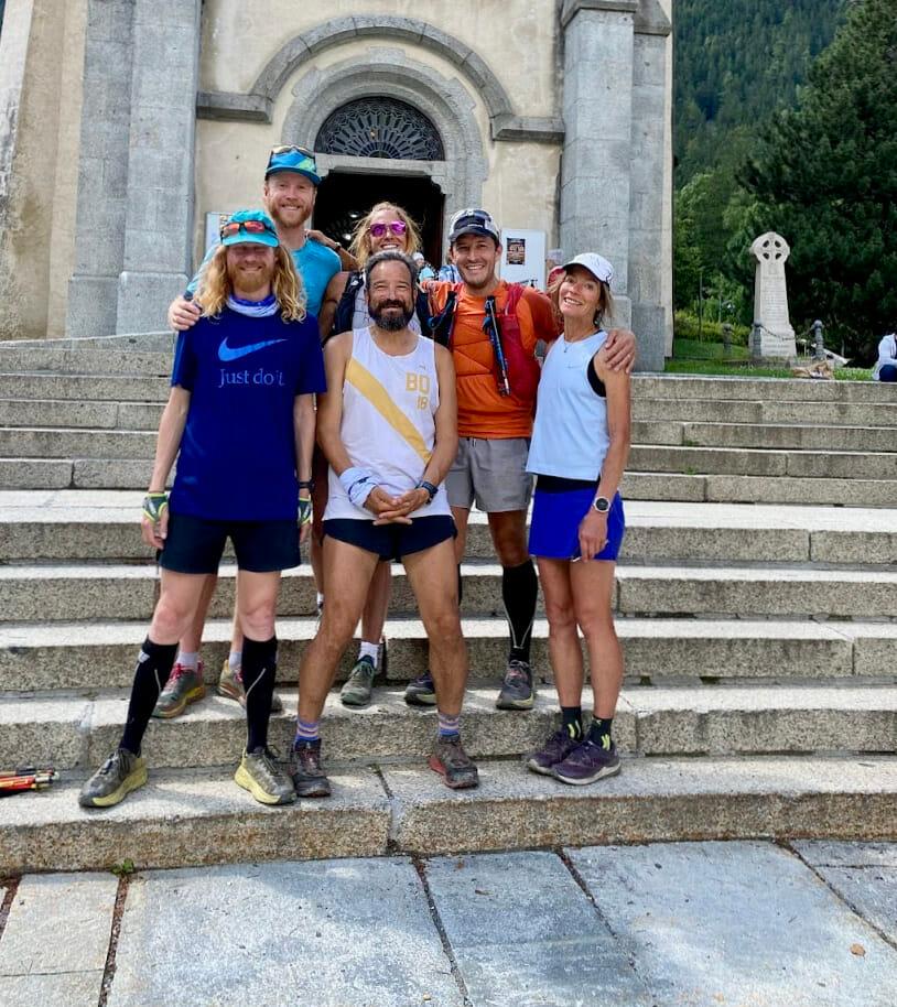 Six trail runners who finished the tour du mont blanc on the church steps in old Chamonix