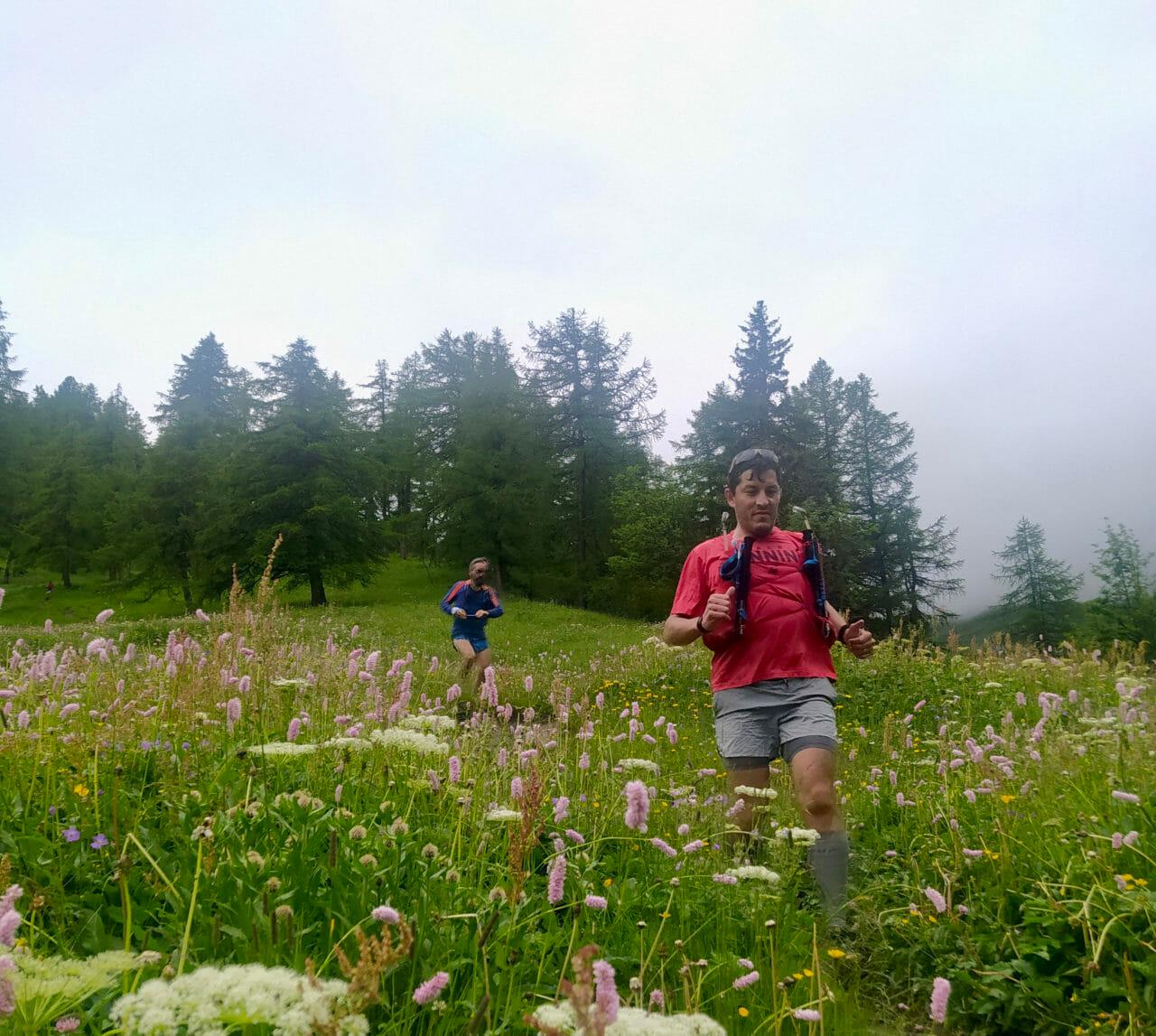 Two male trail runners moving through a pasture with fog in the background